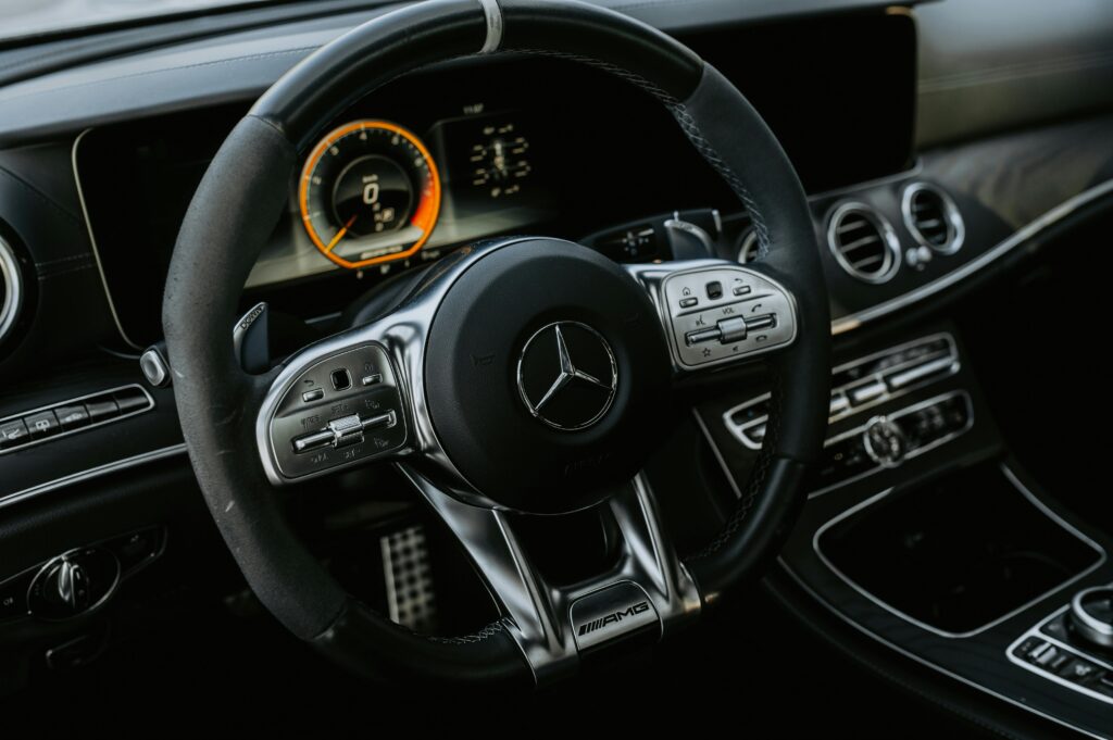 Close-up view of a luxury Mercedes car interior showcasing the steering wheel with controls and dashboard.